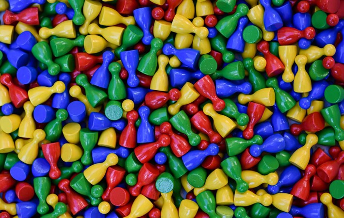 Liegende Spielfiguren in blau, geld, grün und rot.