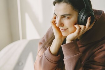 Eine Frau, die einen Kopfhörer trägt und aus dem Fenster schaut.