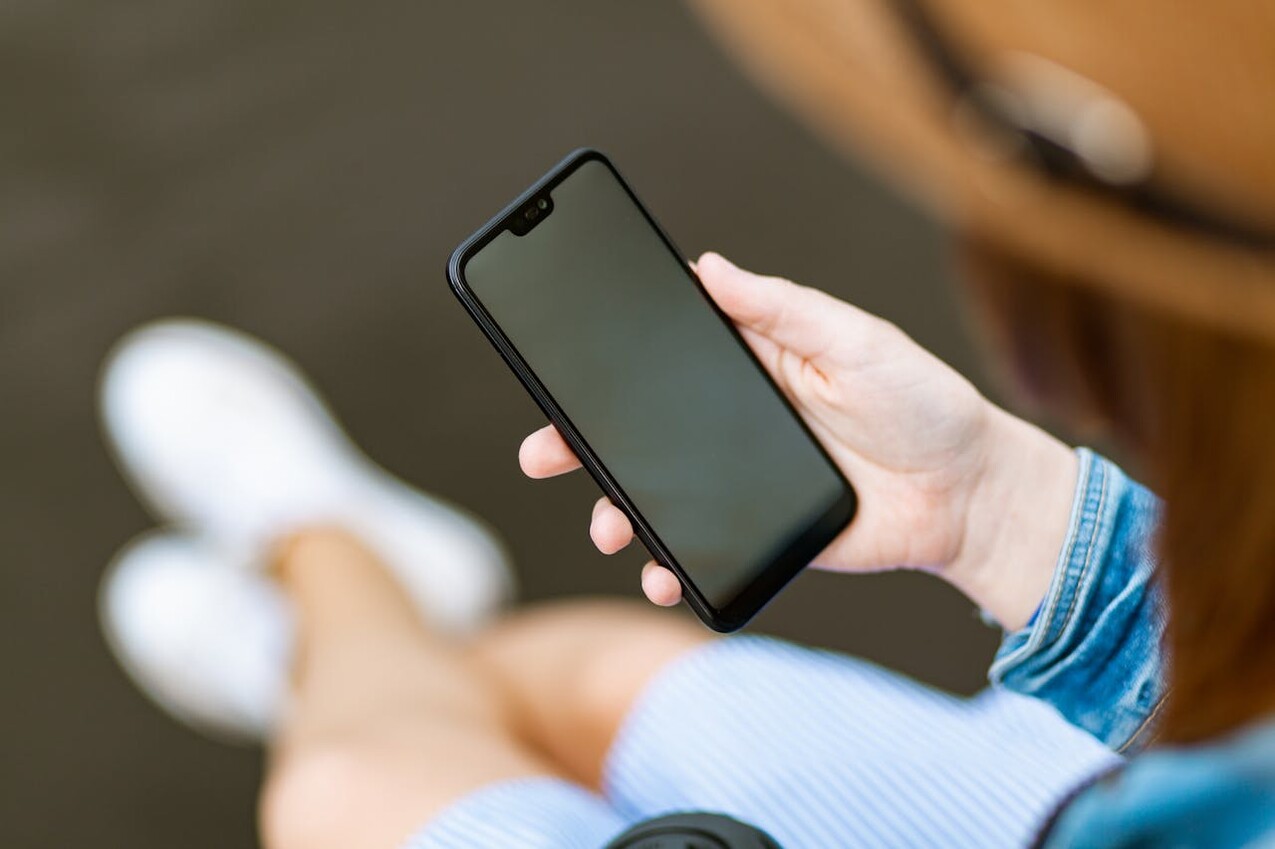 Eine Frau, die ein Smartphone in der Hand hält.